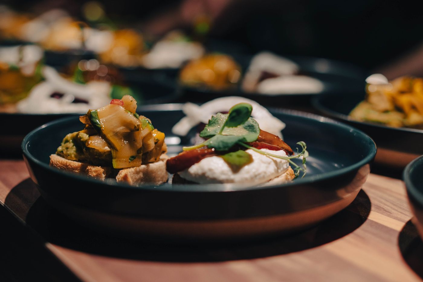 Close-up of two bruschettas on a dark plate