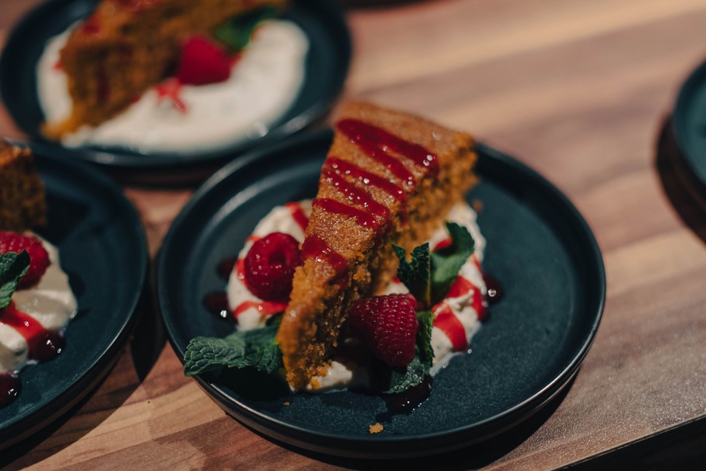 A slice of cake with whipped cream, raspberries and mint