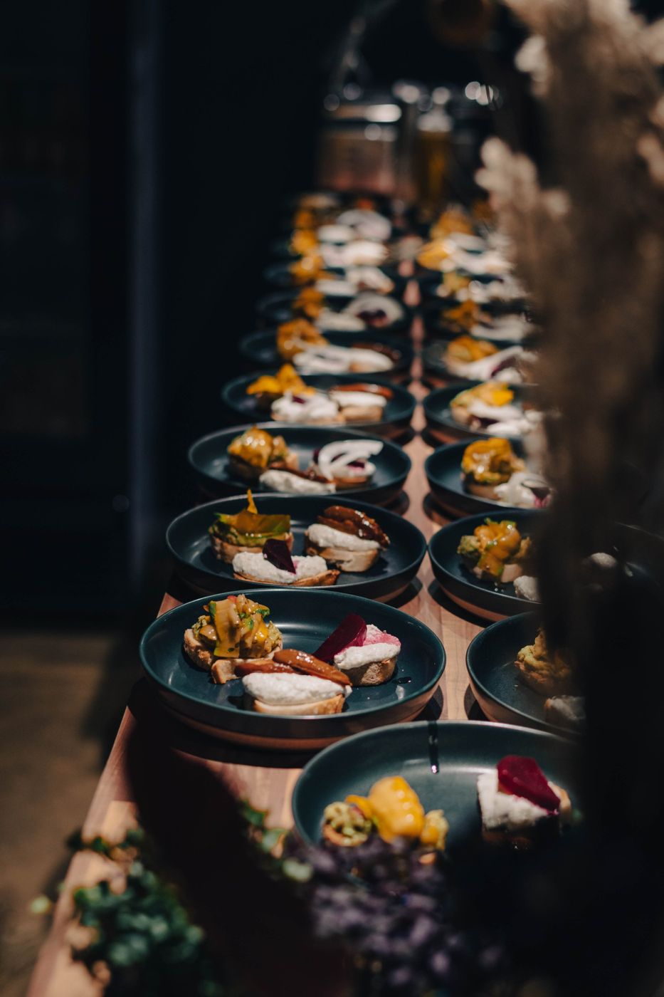 A long row of plated bruschettas waiting to go out
